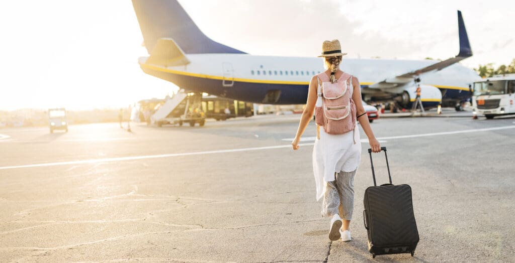 girl pulling suitcase about to board plane